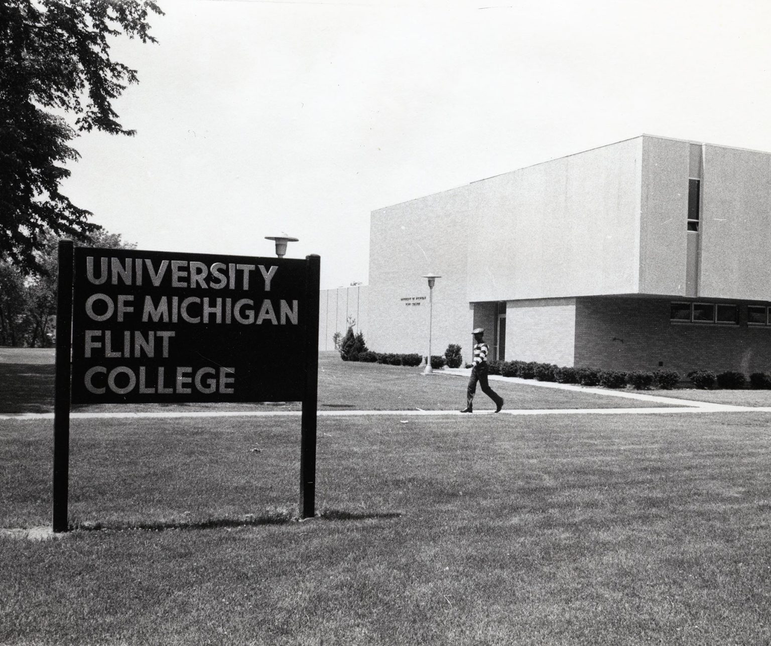 A photo of a young man walking outside U-M Flint College, 1970